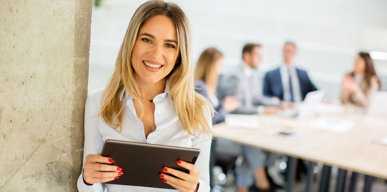 ragazza sorridente con tablet in mano a simboleggiare la digitalizzazione nelle imprese