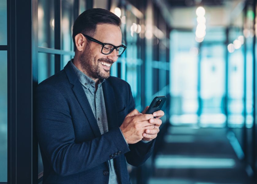 uomo sorridente tiene in mano un cellulare